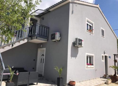 a white house with a staircase and a balcony at Apartman Đokić 3 in Bale
