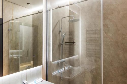 une salle de bain avec une douche en verre avec un lavabo dans l'établissement GlowNest Apartment Near Mega, à Almaty
