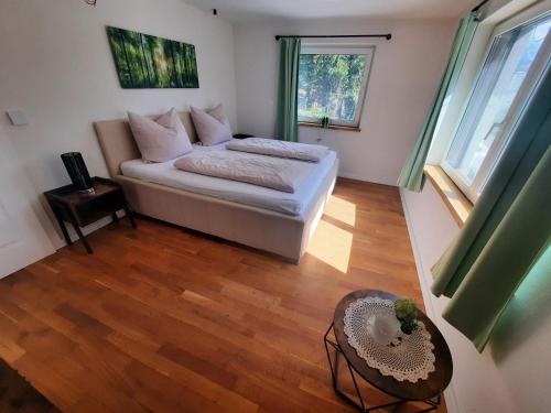 ein Schlafzimmer mit einem Bett und einem Tisch und Fenstern in der Unterkunft Apartment Prinzip Hoffnung in Bürs