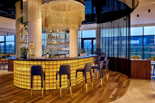 a bar in a restaurant with chairs and windows at Courtyard by Marriott Lyon Eurexpo Stadium in Genas