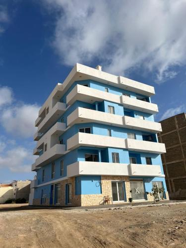 a blue and white apartment building on a dirt road at Appartamenti Praia Estoril, Sal Rei, Boa Vista in Sal Rei