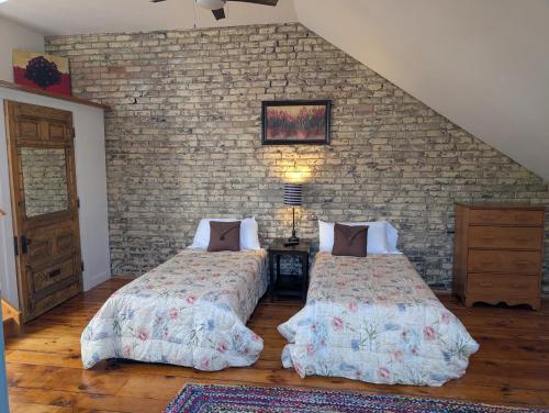 a bedroom with two beds and a brick wall at Cozy 2-Bedroom Downtown Apartment in London