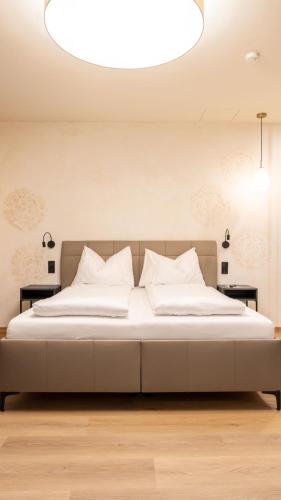 una camera da letto con un grande letto con cuscini bianchi di Aparthotel Lavilo Main Square a Graz