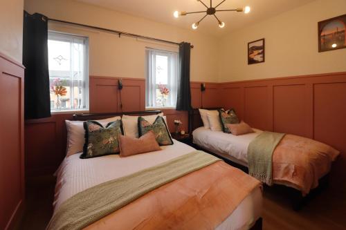 two beds in a room with two windows at Superb Large Bespoke 5 Star Detached Villa, Prime Location, Belfast Stay in Belfast