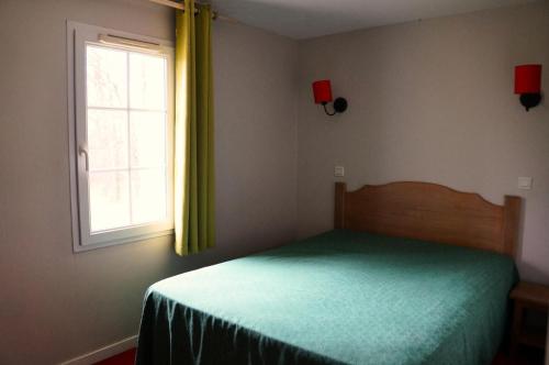 une chambre avec un lit vert et une fenêtre dans l'établissement La résidence du Lac - maeva Home - Maison 3 pièces 6 personnes - Sélection MAE-0364, à Monflanquin