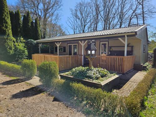 a tiny house with a porch and a garden at Madeliefje - Familie camping in Raalte in Raalte