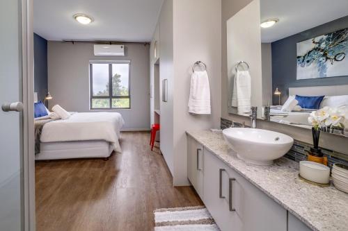 a bathroom with a sink and a bed and a mirror at Urban Oasis Apartment at The Hub in Johannesburg
