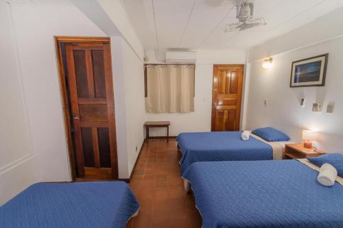 two beds in a room with blue sheets at Hotel el Tajalin in Montezuma