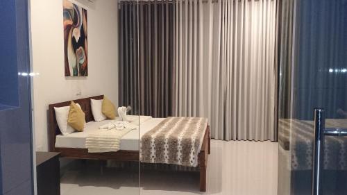 a bedroom with a bed and a window with curtains at Pearl White Residency-HOTEL in Polonnaruwa