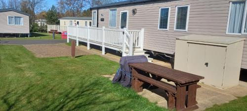 a wooden bench sitting in the grass next to a house at Chill Out at Seton Sands in Port Seton