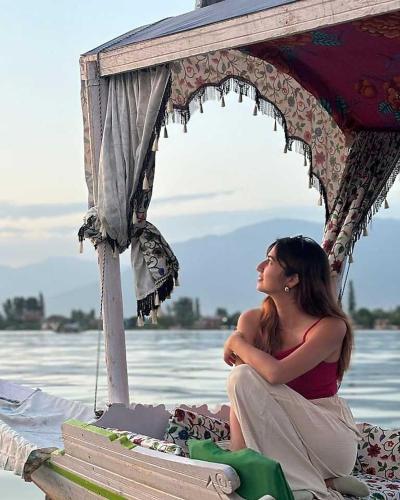 a woman sitting under an umbrella near the water at HB Freedom group of Houseboats in Srinagar
