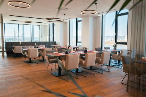 a dining room with tables and chairs and windows at Frames Hotel GmbH in Mülheim-Kärlich