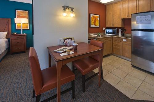 a kitchen with a table with chairs and a refrigerator at Residence Inn by Marriott Fayetteville Cross Creek in Fayetteville