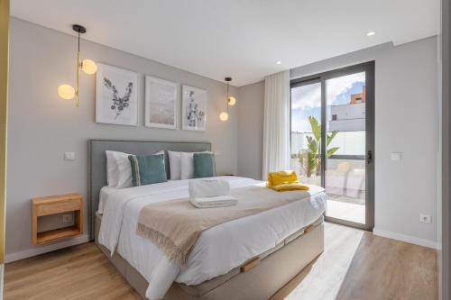 ein weißes Schlafzimmer mit einem großen Bett und einem Fenster in der Unterkunft Casa da Ilha in Funchal