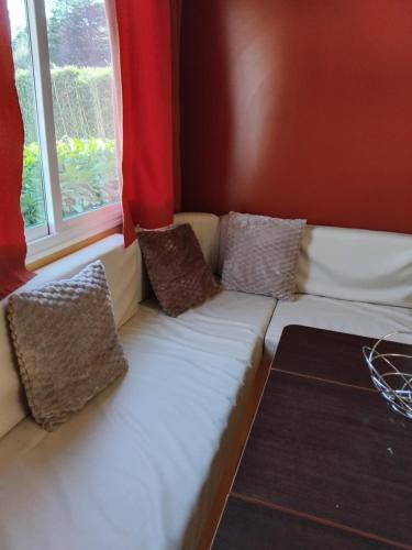 a couch with pillows sitting next to a window at Mobil home LE COUCOU in Le Martinet