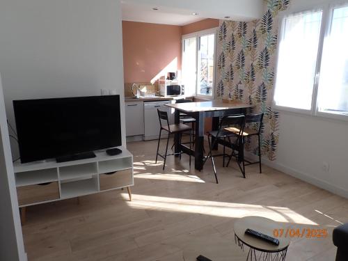 a living room with a television and a table with chairs at Escale montferrandaise in Clermont-Ferrand
