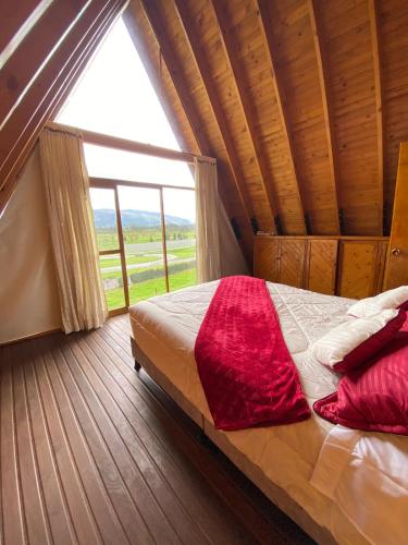 a bed in a room with a large window at La cabaña mirador in Tocancipá