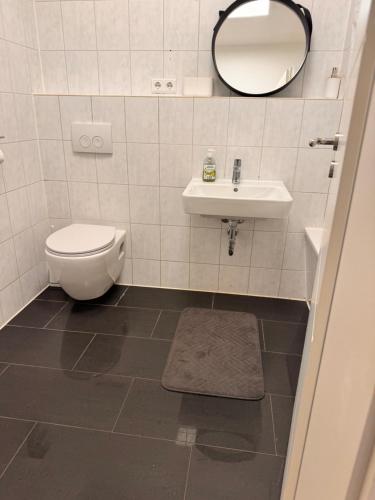 a bathroom with a toilet and a sink and a mirror at A&V Apartments Arena Schalke in Gelsenkirchen