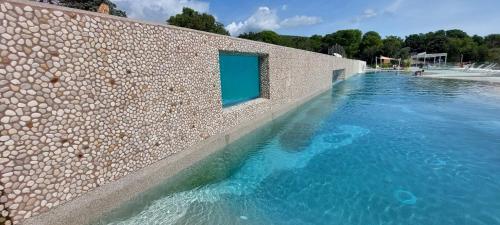 a swimming pool next to a brick wall with a blue window at SEA HOUSE pool & jacuzzi, bikes, SUP - PRIVILEGE POINT camping & villas in Selce