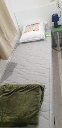 a white bed in a room with a green pillow at MOBIL HOME n 2 TOUT CONFORT ST CYPRIEN 66 in Saint-Cyprien