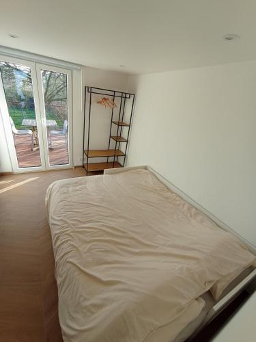 Una cama en una habitación blanca con ventana. en studio L'opale, en Assesse