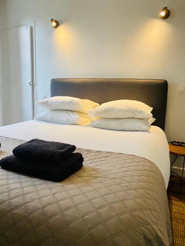 un lit avec des oreillers blancs et une couverture noire dessus dans l'établissement La Petite Maison du Moulin, à Salviac