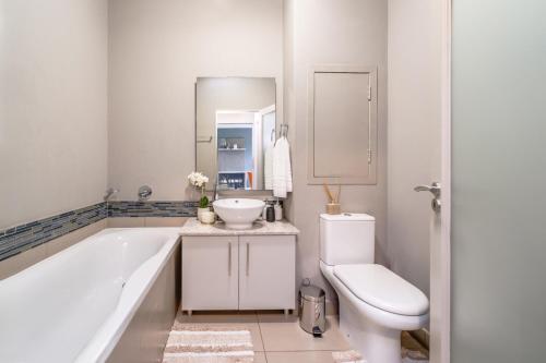 a bathroom with a tub and a sink and a toilet at Urban Oasis Apartment at The Hub in Johannesburg