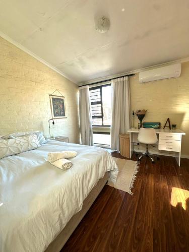 a bedroom with a large white bed and a desk at Comfy full apartment in Stellenbosch