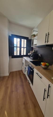 a kitchen with white cabinets and a wooden floor at Apartamento El Encanto descanso y Naturaleza in Cazorla