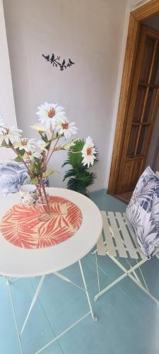 a white table with a vase with flowers on it at Apartamento El Encanto descanso y Naturaleza in Cazorla