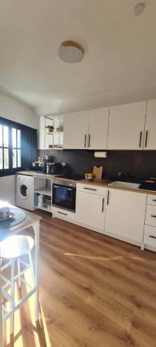 a kitchen with white cabinets and a wooden floor at Apartamento El Encanto descanso y Naturaleza in Cazorla