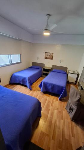 two beds in a room with blue sheets at Hotel Mayoral in Rosario