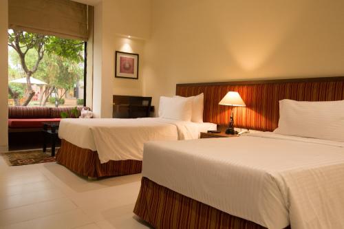Habitación de hotel con 2 camas y sofá en Lemon Tree Hotel, Tarudhan Valley, Manesar, en Gurgaon
