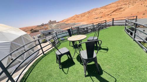 a balcony with a table and chairs on the grass at شاليه الروح AlRooh Chalet in Al Raka