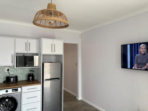 eine Küche mit einem Kühlschrank aus Edelstahl und einem TV in der Unterkunft Comfy Cottage in Walvis Bay