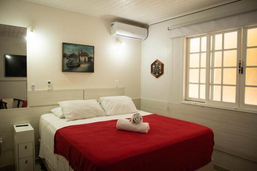 a bedroom with a bed with a red blanket and a window at Bouganville Suites in Angra dos Reis