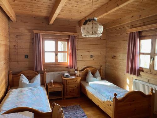 two beds in a room with wooden walls and windows at Berg-Panorama-Ferienwohnungen Gut-Lichtenau in Hauzenberg