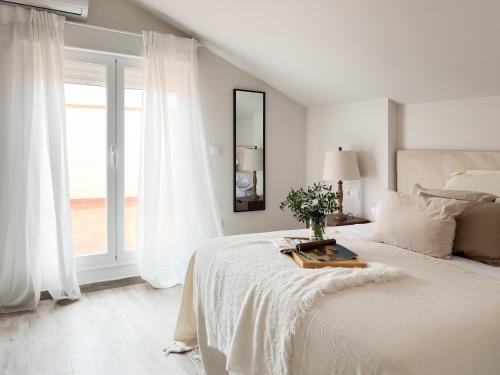 a white bedroom with a bed and a window at ChillaHomes 103 in Candeleda