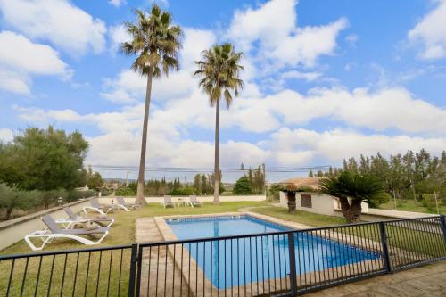 a villa with a swimming pool and palm trees at Ses Covetes, Hidromasaje, Piscina y Barbacoa in Petra