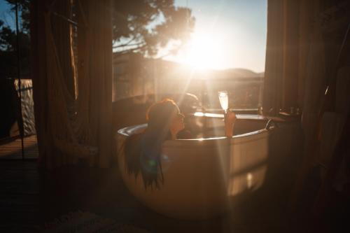 a young girl sitting in a bath tub with the sun shining at Vila dos Cedros in Rio dos Cedros