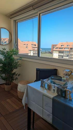 une pièce avec une table et une grande fenêtre dans l'établissement E comme Eden, 2 pièces vue mer loggia et parking, à Villers-sur-Mer