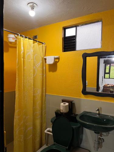a bathroom with a yellow shower curtain and a sink at La cabaña de la abuela in Sutatausa