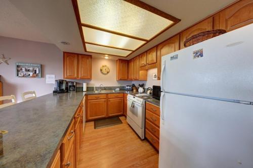 a kitchen with a white refrigerator and wooden cabinets at Cannon Beach Condo Ocean Views ! Close to Beach! in Cannon Beach