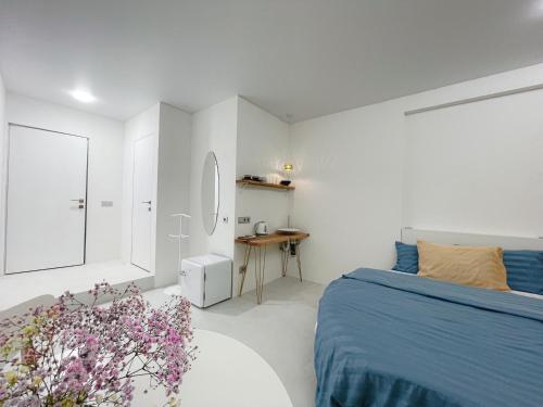 a white bedroom with a blue bed and a table at Studia-Focus-Design in Aktobe