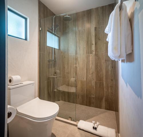 a bathroom with a toilet and a glass shower at Lia Hotel Jaco in Jacó