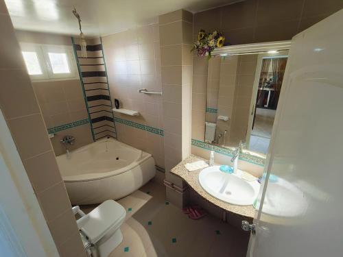 a bathroom with a toilet and a sink and a tub at DarNour in ‘Alāqimah