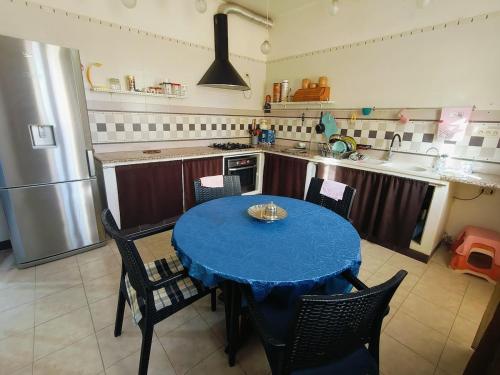 a kitchen with a blue table with chairs and a refrigerator at DarNour in ‘Alāqimah