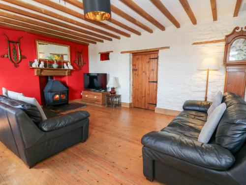 a living room with a leather couch and a television at The Farmhouse in Ciliau-Aeron