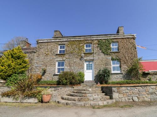 an old stone house with a white door at The Farmhouse in Ciliau-Aeron
