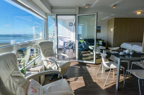 a room with chairs and a balcony with the ocean at Haus Frische Brise 1507 in Cuxhaven